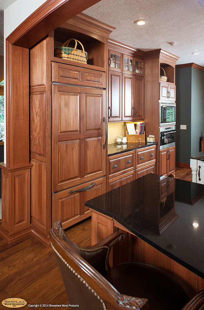 他の地域にあるトラディショナルスタイルのおしゃれなキッチン (レイズドパネル扉のキャビネット、御影石カウンター、パネルと同色の調理設備) の写真