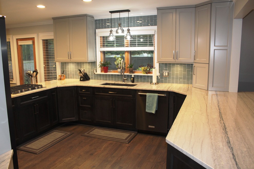 This is an example of a large traditional u-shaped kitchen/diner in Detroit with a submerged sink, recessed-panel cabinets, grey cabinets, quartz worktops, blue splashback, glass tiled splashback, stainless steel appliances, medium hardwood flooring, a breakfast bar, brown floors and multicoloured worktops.