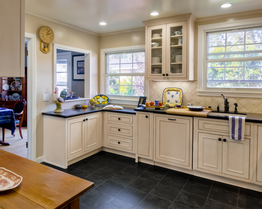 Example of a classic slate floor kitchen design in San Francisco with an undermount sink, beaded inset cabinets, distressed cabinets, white backsplash and paneled appliances