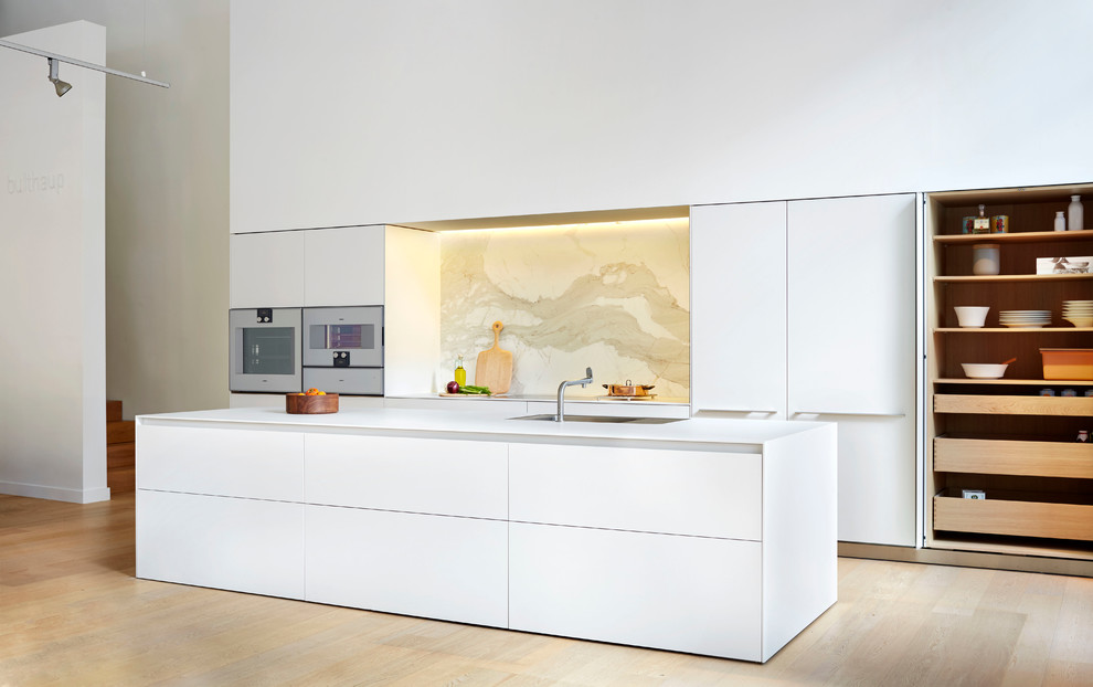 Bild på ett stort funkis kök och matrum, med en integrerad diskho, släta luckor, vita skåp, laminatbänkskiva, stänkskydd i sten, en köksö och integrerade vitvaror