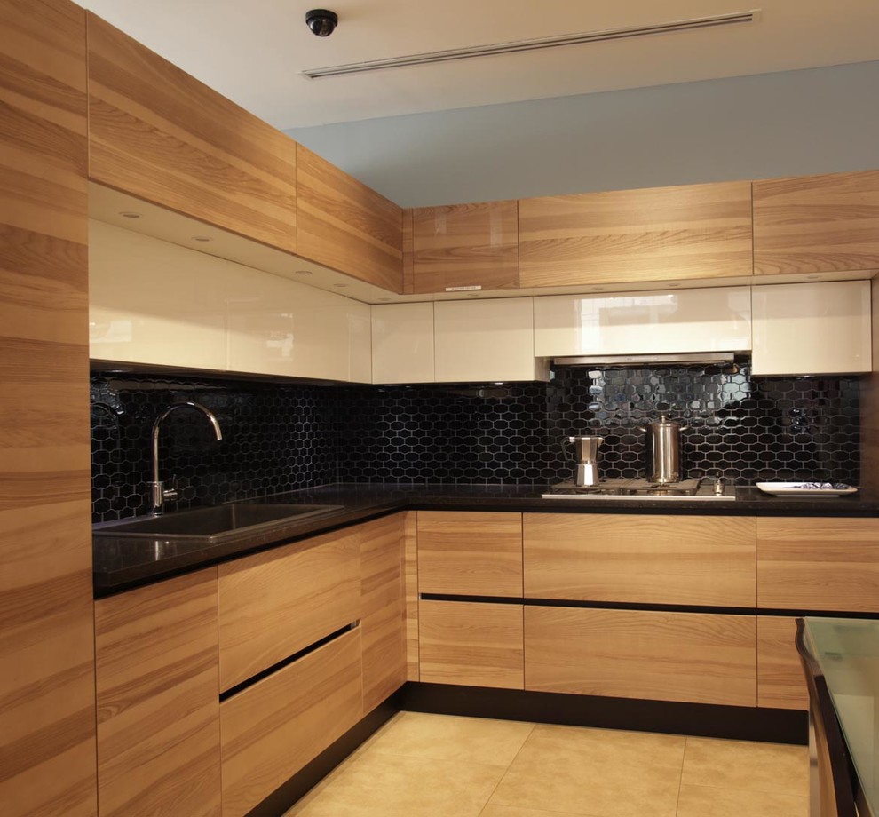 Inspiration for a large modern l-shaped kitchen pantry in New York with a built-in sink, flat-panel cabinets, light wood cabinets, composite countertops, black splashback, stainless steel appliances, ceramic flooring, an island and glass tiled splashback.