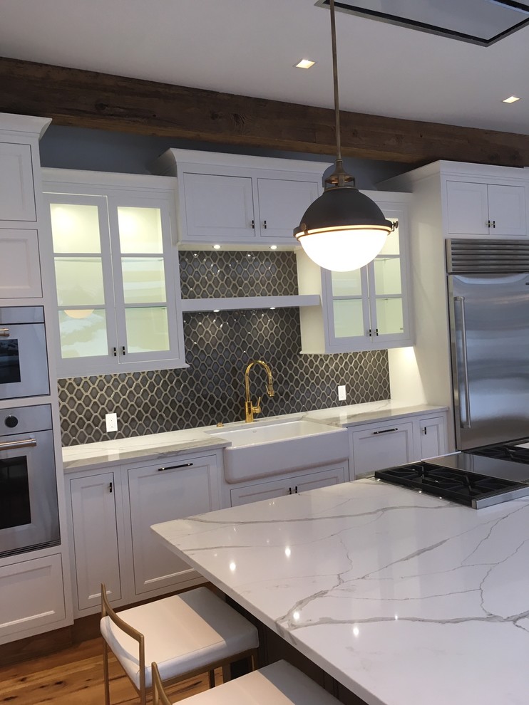 Exempel på ett mycket stort klassiskt vit linjärt vitt kök och matrum, med en rustik diskho, skåp i shakerstil, vita skåp, bänkskiva i kvarts, brunt stänkskydd, stänkskydd i keramik, rostfria vitvaror, ljust trägolv, en köksö och gult golv