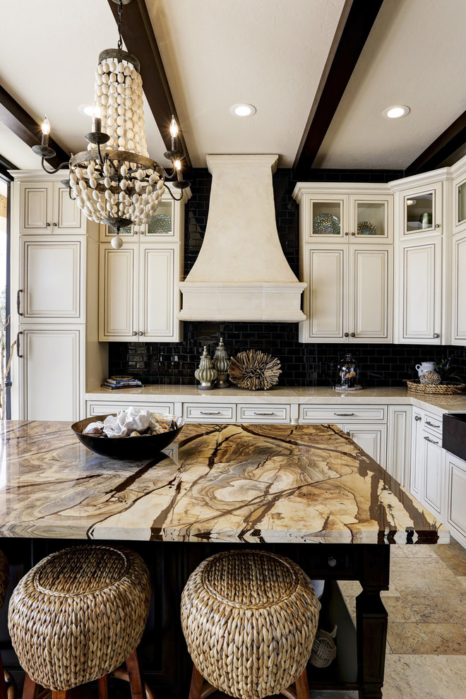 Eat-in kitchen - mid-sized traditional l-shaped porcelain tile eat-in kitchen idea in Houston with a farmhouse sink, raised-panel cabinets, white cabinets, quartzite countertops, black backsplash, subway tile backsplash, stainless steel appliances and an island