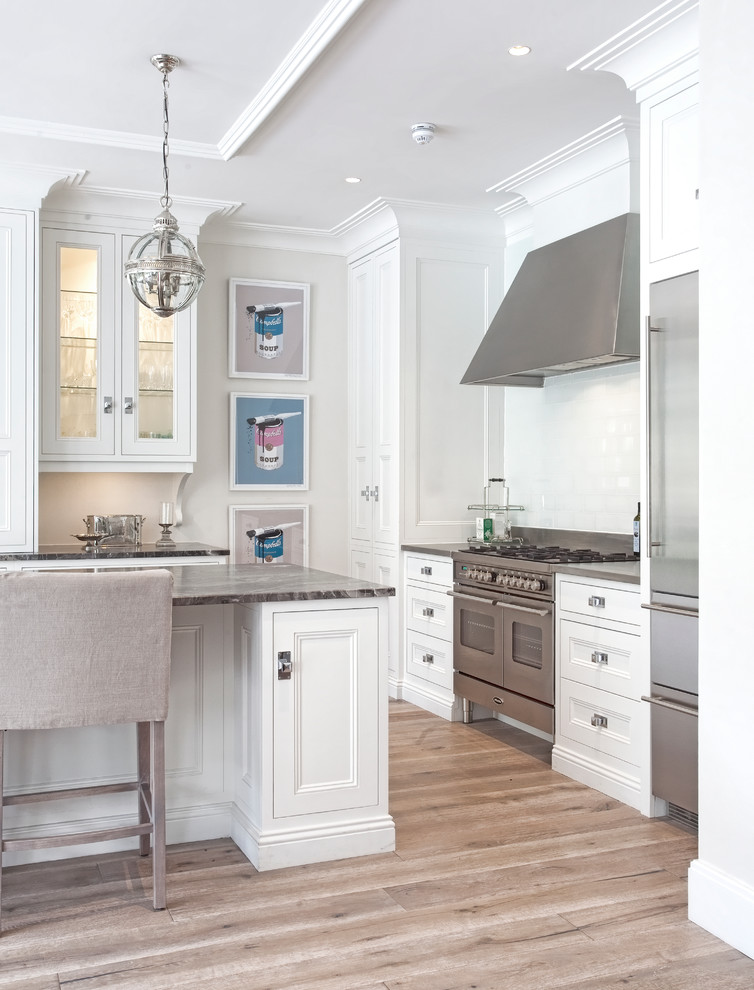 Large classic l-shaped kitchen/diner in Dublin with a submerged sink, beaded cabinets, white cabinets, marble worktops, white splashback, glass tiled splashback, stainless steel appliances, medium hardwood flooring and an island.