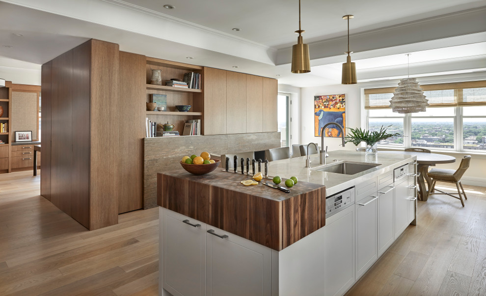 Design ideas for a large contemporary kitchen/diner in Chicago with a submerged sink, flat-panel cabinets, white cabinets, quartz worktops, integrated appliances, light hardwood flooring, an island, brown floors, white worktops and a drop ceiling.