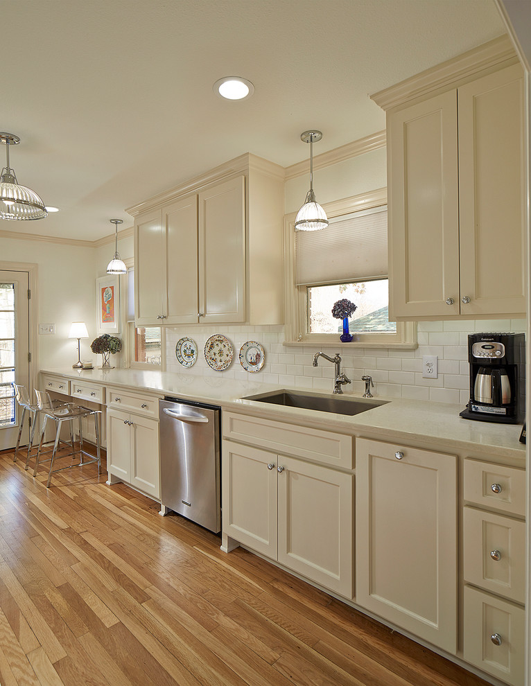 Enclosed kitchen - mid-sized traditional galley light wood floor and brown floor enclosed kitchen idea in Dallas with an undermount sink, shaker cabinets, white cabinets, quartz countertops, white backsplash, subway tile backsplash, stainless steel appliances and no island