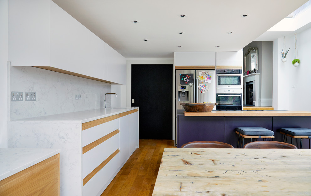 Exempel på ett stort modernt kök, med en integrerad diskho, släta luckor, vita skåp, bänkskiva i koppar, vitt stänkskydd, stänkskydd i sten, rostfria vitvaror, mellanmörkt trägolv, en köksö och brunt golv
