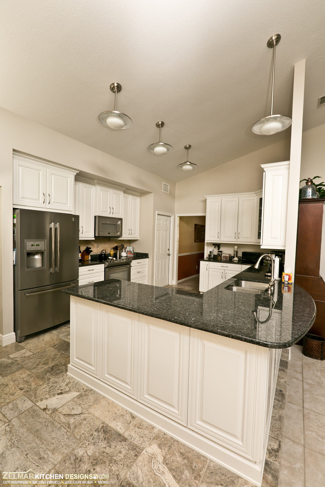 Eat-in kitchen - mid-sized transitional u-shaped travertine floor eat-in kitchen idea in Orlando with raised-panel cabinets, granite countertops, beige backsplash, stone tile backsplash and a peninsula