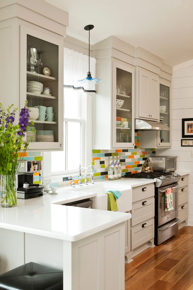 Cette photo montre une cuisine chic avec un plan de travail en quartz modifié, une crédence multicolore, des portes de placard grises, un placard à porte vitrée et un électroménager en acier inoxydable.