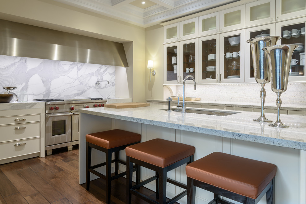 Exempel på ett avskilt, stort klassiskt l-kök, med vita skåp, granitbänkskiva, rostfria vitvaror, mellanmörkt trägolv, en köksö, stänkskydd i sten, en undermonterad diskho, luckor med glaspanel, vitt stänkskydd och brunt golv