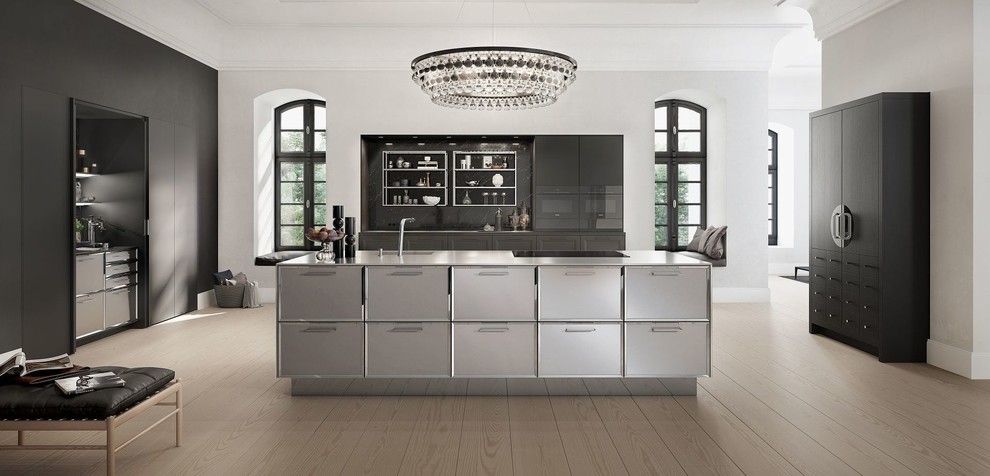 Klassisk inredning av ett stort grå grått kök, med en nedsänkt diskho, grå skåp, bänkskiva i rostfritt stål, stänkskydd i keramik, integrerade vitvaror, ljust trägolv, en köksö, brunt golv, flerfärgad stänkskydd och luckor med infälld panel