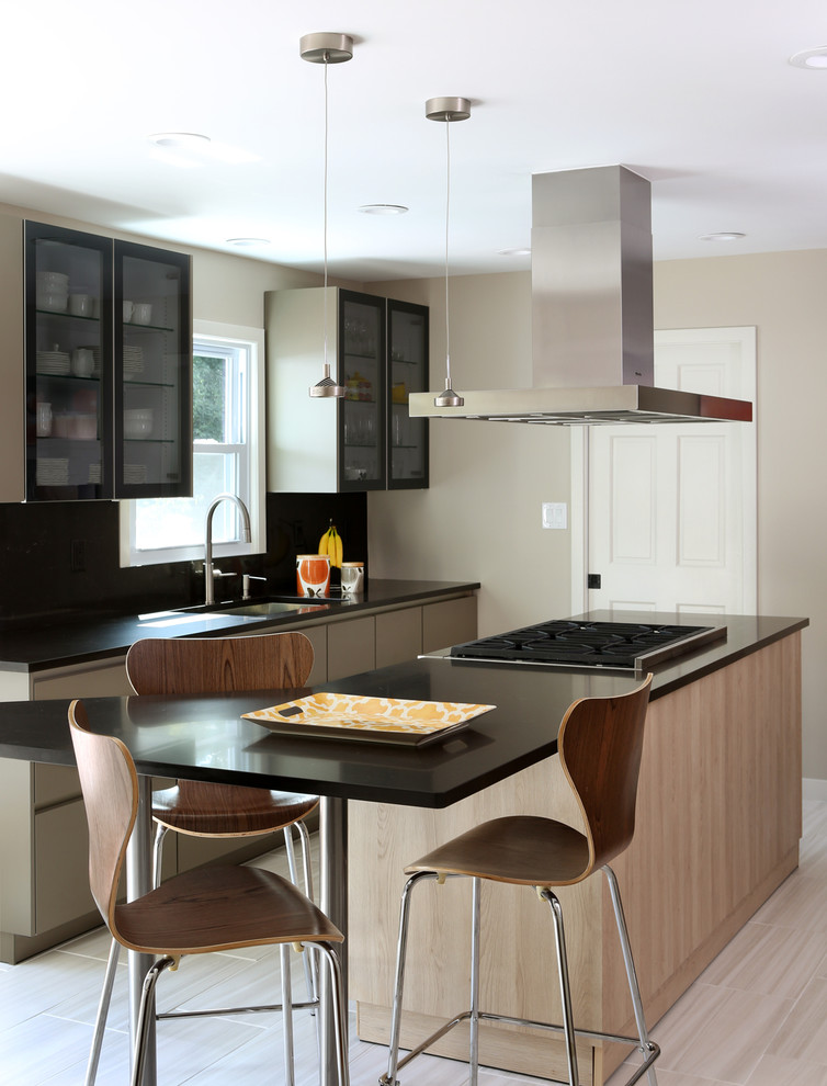 Foto di un cucina con isola centrale design con lavello sottopiano, top in quarzo composito, paraspruzzi nero e ante di vetro