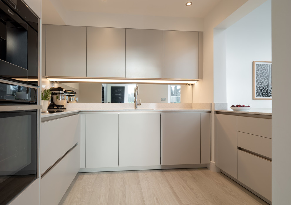 Kleine Moderne Wohnküche mit flächenbündigen Schrankfronten, grauen Schränken und Quarzwerkstein-Arbeitsplatte in Sonstige