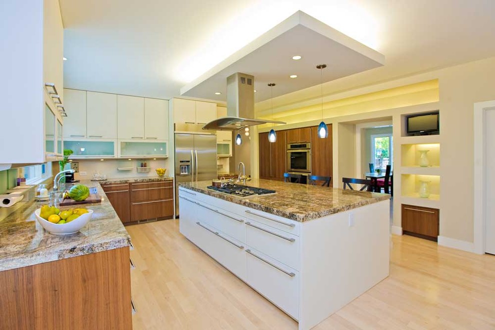 Photo of a large contemporary u-shaped open plan kitchen in San Francisco with flat-panel cabinets, white cabinets, granite worktops, stainless steel appliances, a submerged sink, white splashback, light hardwood flooring, an island, beige floors and multicoloured worktops.