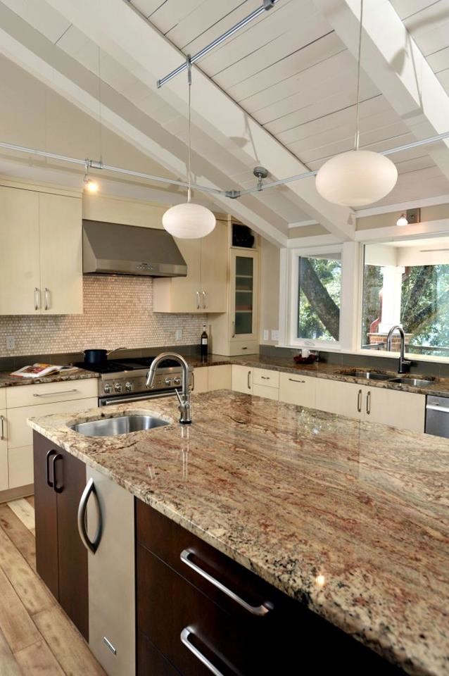 Exempel på ett modernt kök, med en undermonterad diskho, släta luckor, rostfria vitvaror, en köksö och granitbänkskiva
