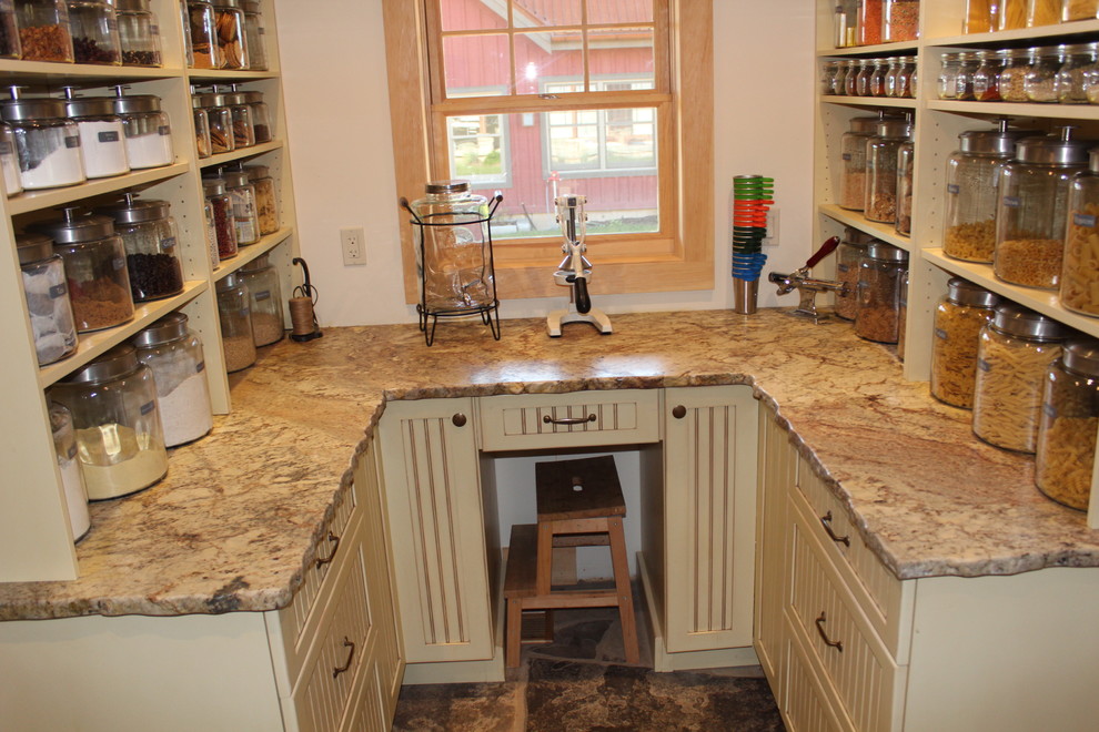 Rustikale Küche in U-Form mit Granit-Arbeitsplatte, Vorratsschrank, Landhausspüle, gelben Schränken, Rückwand aus Steinfliesen und braunem Holzboden in Toronto