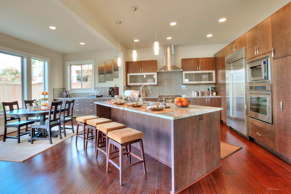 シアトルにあるトランジショナルスタイルのおしゃれなキッチン (フラットパネル扉のキャビネット、中間色木目調キャビネット、グレーのキッチンパネル、サブウェイタイルのキッチンパネル、シルバーの調理設備) の写真