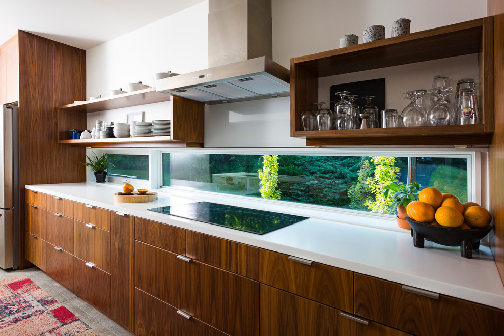 Esempio di una piccola cucina minimal con ante lisce, ante in legno scuro, top in superficie solida, elettrodomestici in acciaio inossidabile e pavimento in cemento
