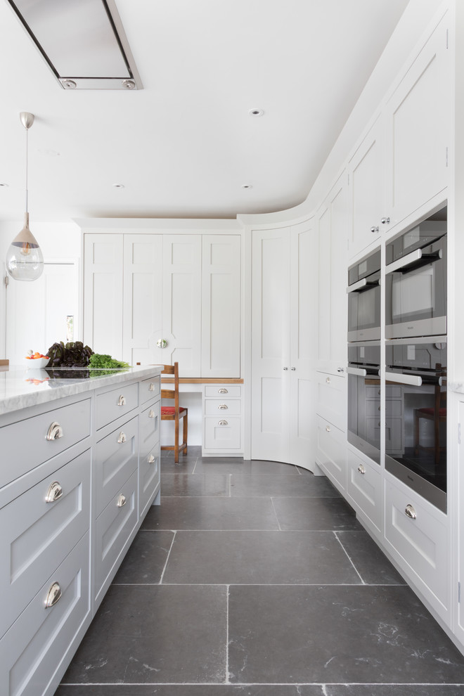 Example of a large transitional gray floor open concept kitchen design in Hampshire with shaker cabinets, black appliances and an island