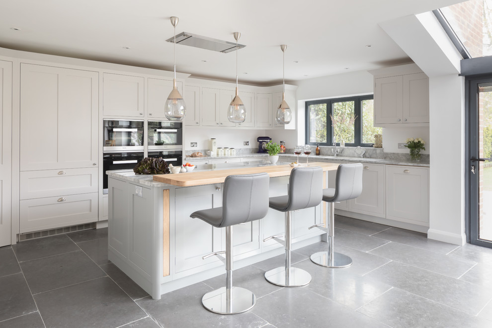 Offene, Große Klassische Küche mit Schrankfronten im Shaker-Stil, schwarzen Elektrogeräten, Kücheninsel und grauem Boden in Surrey