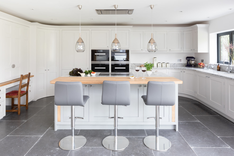 Große Klassische Küche in grau-weiß mit Schrankfronten im Shaker-Stil, schwarzen Elektrogeräten, Kücheninsel, grauem Boden, Unterbauwaschbecken und weißen Schränken in Surrey