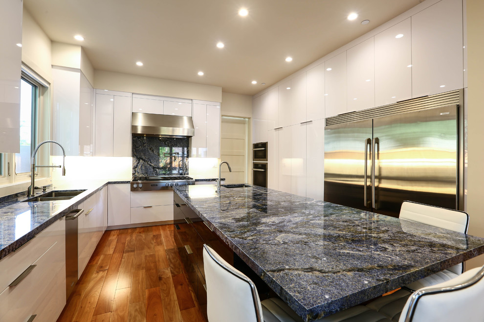 This is an example of a large contemporary galley open plan kitchen in San Francisco with a single-bowl sink, flat-panel cabinets, yellow cabinets, granite worktops, white splashback, glass sheet splashback, stainless steel appliances, medium hardwood flooring, an island and blue floors.