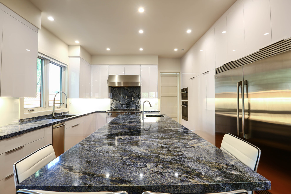 Large trendy galley medium tone wood floor and blue floor open concept kitchen photo in San Francisco with a single-bowl sink, flat-panel cabinets, yellow cabinets, granite countertops, white backsplash, glass sheet backsplash, stainless steel appliances and an island