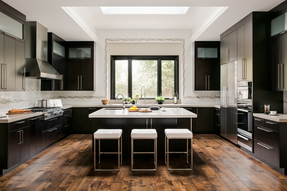 Large trendy u-shaped dark wood floor and brown floor open concept kitchen photo in Atlanta with a double-bowl sink, flat-panel cabinets, dark wood cabinets, quartzite countertops, white backsplash, ceramic backsplash, stainless steel appliances and an island