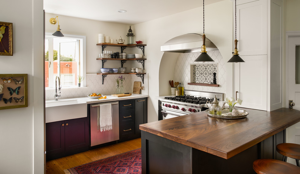 Exempel på ett mellanstort medelhavsstil vit vitt kök, med en rustik diskho, luckor med infälld panel, marmorbänkskiva, vitt stänkskydd, stänkskydd i porslinskakel, rostfria vitvaror, mellanmörkt trägolv, en halv köksö, svarta skåp och brunt golv