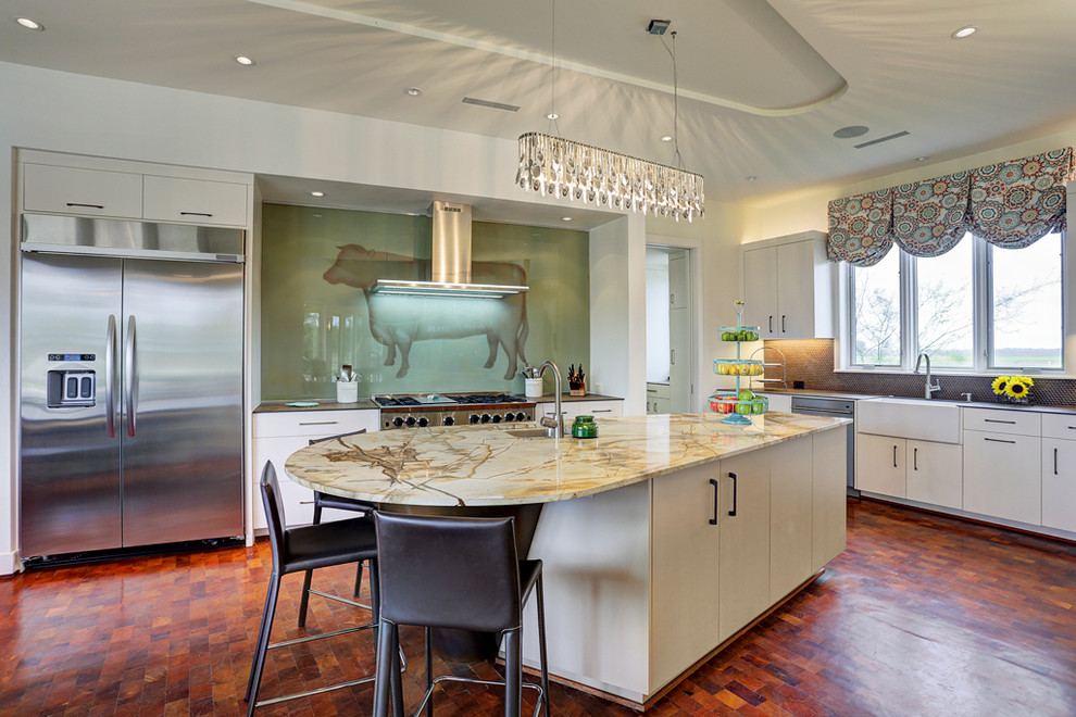 Example of a large trendy l-shaped medium tone wood floor and brown floor eat-in kitchen design in Houston with a farmhouse sink, flat-panel cabinets, white cabinets, brown backsplash, an island, granite countertops, glass sheet backsplash and stainless steel appliances