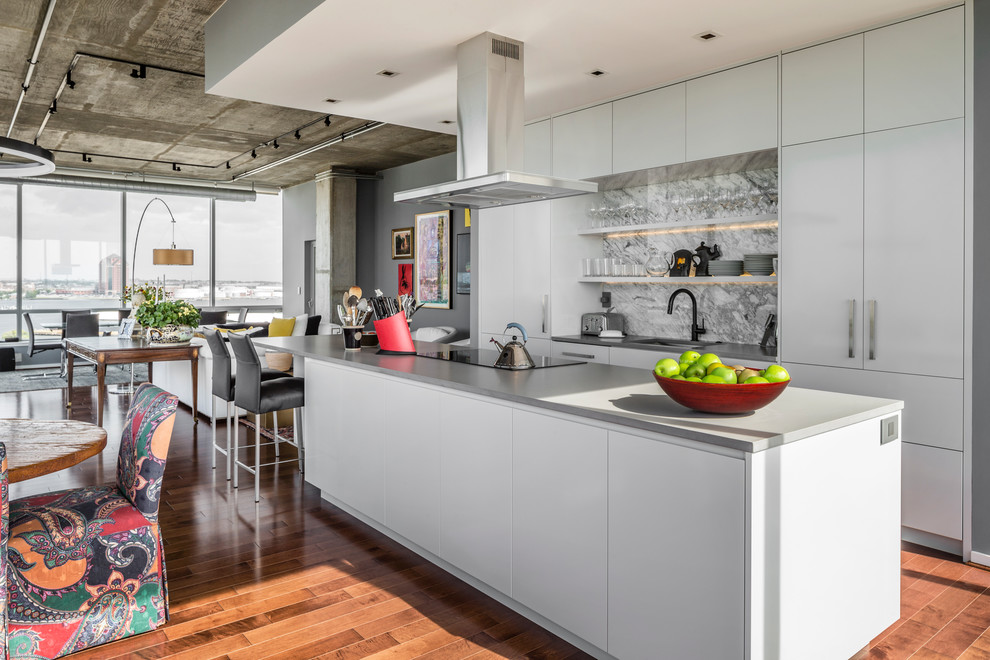 Example of a huge trendy galley medium tone wood floor open concept kitchen design in Baltimore with an undermount sink, flat-panel cabinets, white cabinets, quartz countertops, gray backsplash, paneled appliances and an island