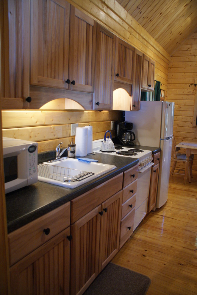 Cette image montre une cuisine ouverte linéaire chalet en bois clair avec un évier posé, un placard à porte affleurante, un plan de travail en stratifié et un électroménager blanc.