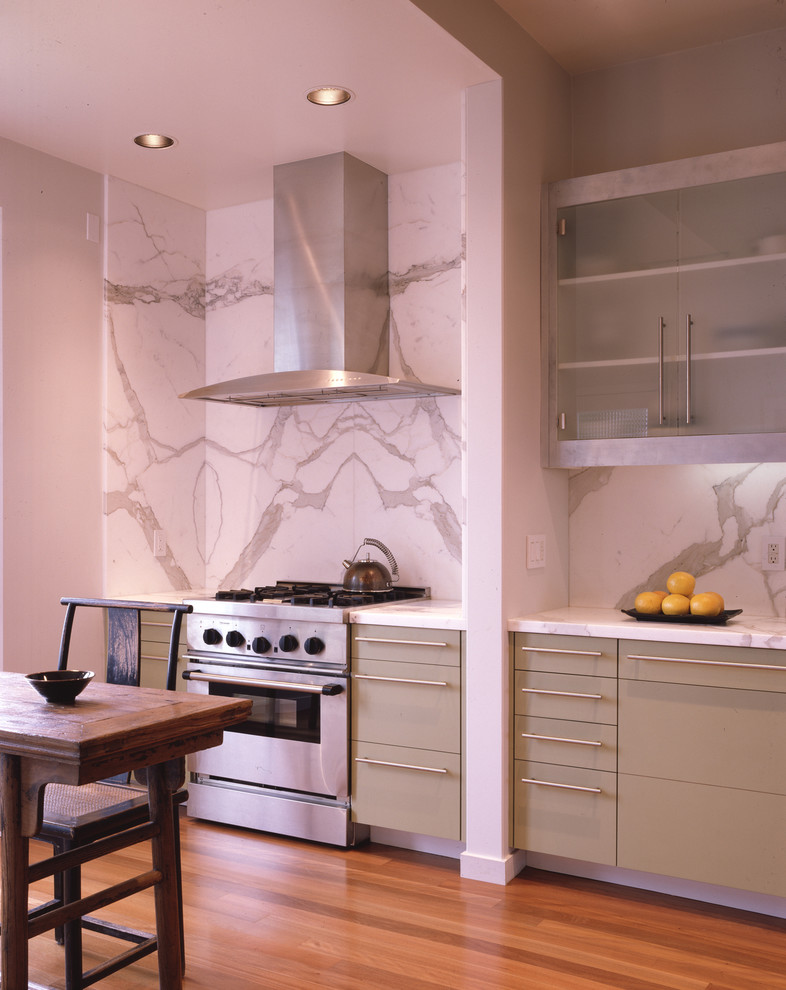 Inredning av ett modernt kök, med rostfria vitvaror, marmorbänkskiva, släta luckor, grå skåp, vitt stänkskydd och stänkskydd i marmor