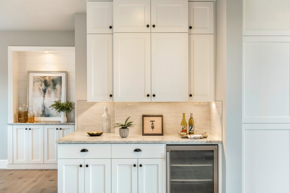 Inspiration for a large classic l-shaped kitchen pantry in Portland with shaker cabinets, white cabinets, engineered stone countertops, grey splashback, ceramic splashback, stainless steel appliances, light hardwood flooring, grey floors and white worktops.
