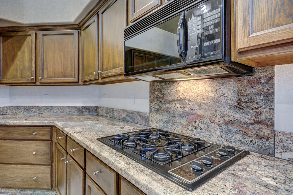 Inredning av ett rustikt avskilt u-kök, med en dubbel diskho, granitbänkskiva, brunt stänkskydd, stänkskydd i sten, svarta vitvaror och en köksö