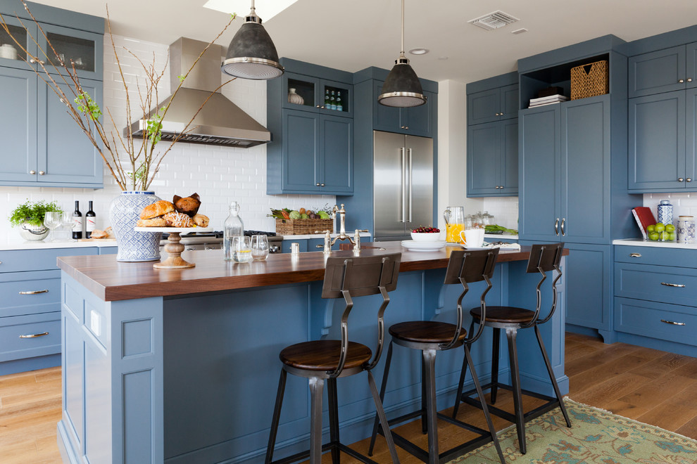 Inspiration for a traditional kitchen in Los Angeles with shaker cabinets, blue cabinets, wood worktops, white splashback, ceramic splashback, stainless steel appliances, medium hardwood flooring and an island.