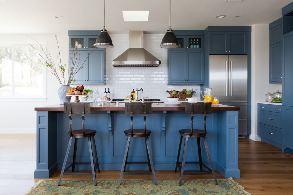 Inspiration for a transitional l-shaped dark wood floor kitchen remodel in Los Angeles with shaker cabinets, blue cabinets, white backsplash, subway tile backsplash, stainless steel appliances and an island