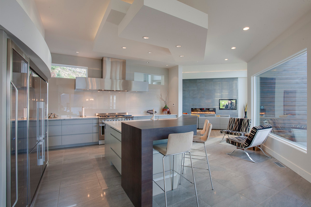 На фото: кухня-гостиная в современном стиле с плоскими фасадами, серыми фасадами и техникой из нержавеющей стали с