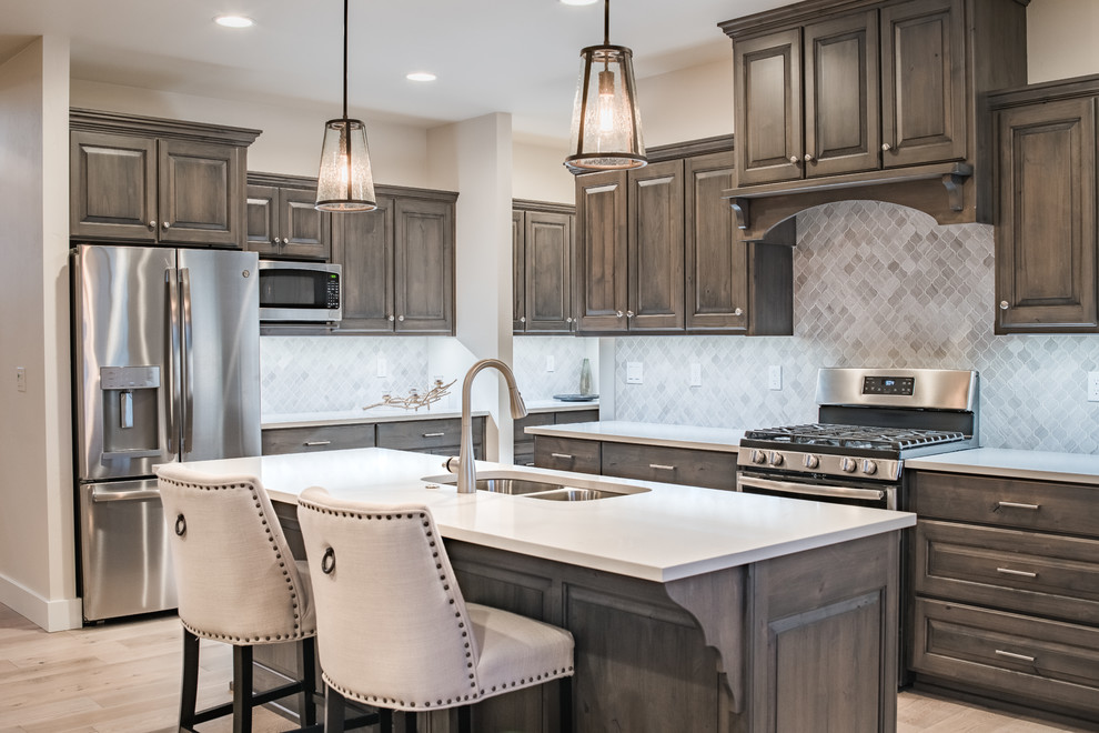 Example of a large transitional l-shaped light wood floor and beige floor kitchen design in Other with a double-bowl sink, raised-panel cabinets, quartz countertops, gray backsplash, ceramic backsplash, stainless steel appliances, an island, white countertops and dark wood cabinets