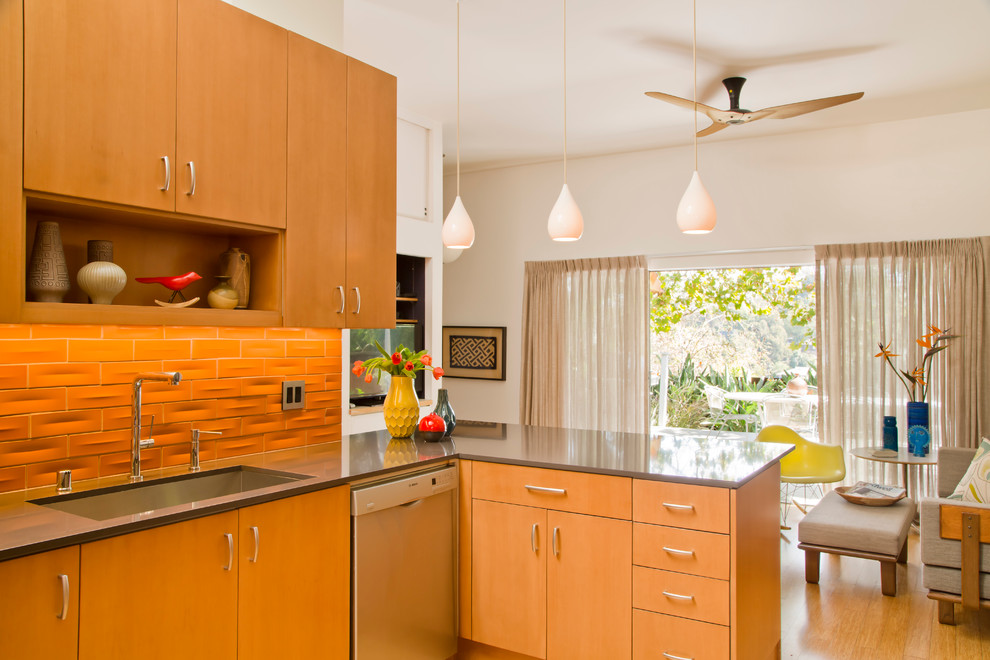 Exempel på ett mellanstort retro kök, med en nedsänkt diskho, släta luckor, skåp i ljust trä, orange stänkskydd, rostfria vitvaror och ljust trägolv
