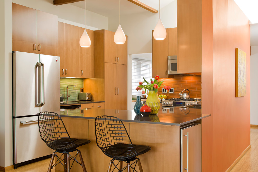 Пример оригинального дизайна: угловая кухня-гостиная среднего размера в стиле ретро с накладной мойкой, плоскими фасадами, светлыми деревянными фасадами, оранжевым фартуком, техникой из нержавеющей стали и светлым паркетным полом без острова