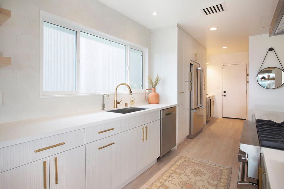 Example of a mid-sized danish u-shaped light wood floor and beige floor eat-in kitchen design in Los Angeles with an undermount sink, flat-panel cabinets, white cabinets, quartz countertops, white backsplash, stainless steel appliances, an island and white countertops