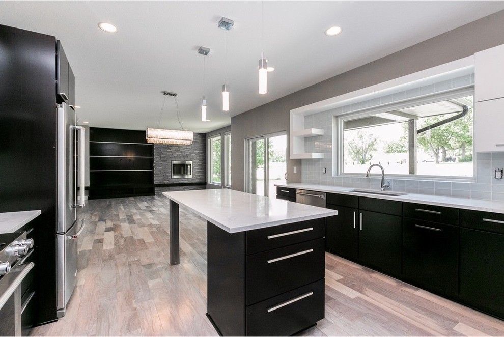 Mid-sized minimalist galley light wood floor and gray floor eat-in kitchen photo in Other with a single-bowl sink, flat-panel cabinets, dark wood cabinets, quartzite countertops, white backsplash, glass tile backsplash, stainless steel appliances and an island