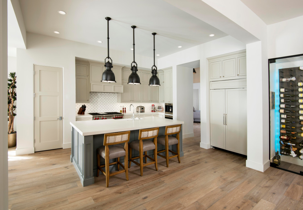 Inspiration for a transitional l-shaped medium tone wood floor and brown floor open concept kitchen remodel in Phoenix with beige cabinets, white backsplash, paneled appliances, an island and white countertops