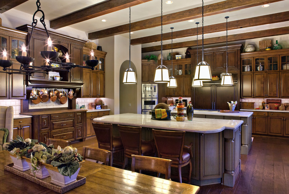Example of a large tuscan u-shaped dark wood floor eat-in kitchen design in Phoenix with raised-panel cabinets, dark wood cabinets, granite countertops, beige backsplash, ceramic backsplash, paneled appliances and an island