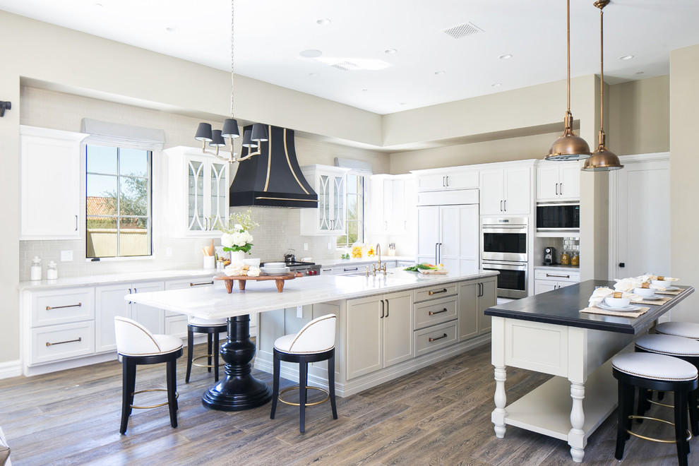 Kitchen - mediterranean medium tone wood floor kitchen idea in Phoenix with an integrated sink, white cabinets, quartz countertops, gray backsplash, stainless steel appliances and two islands