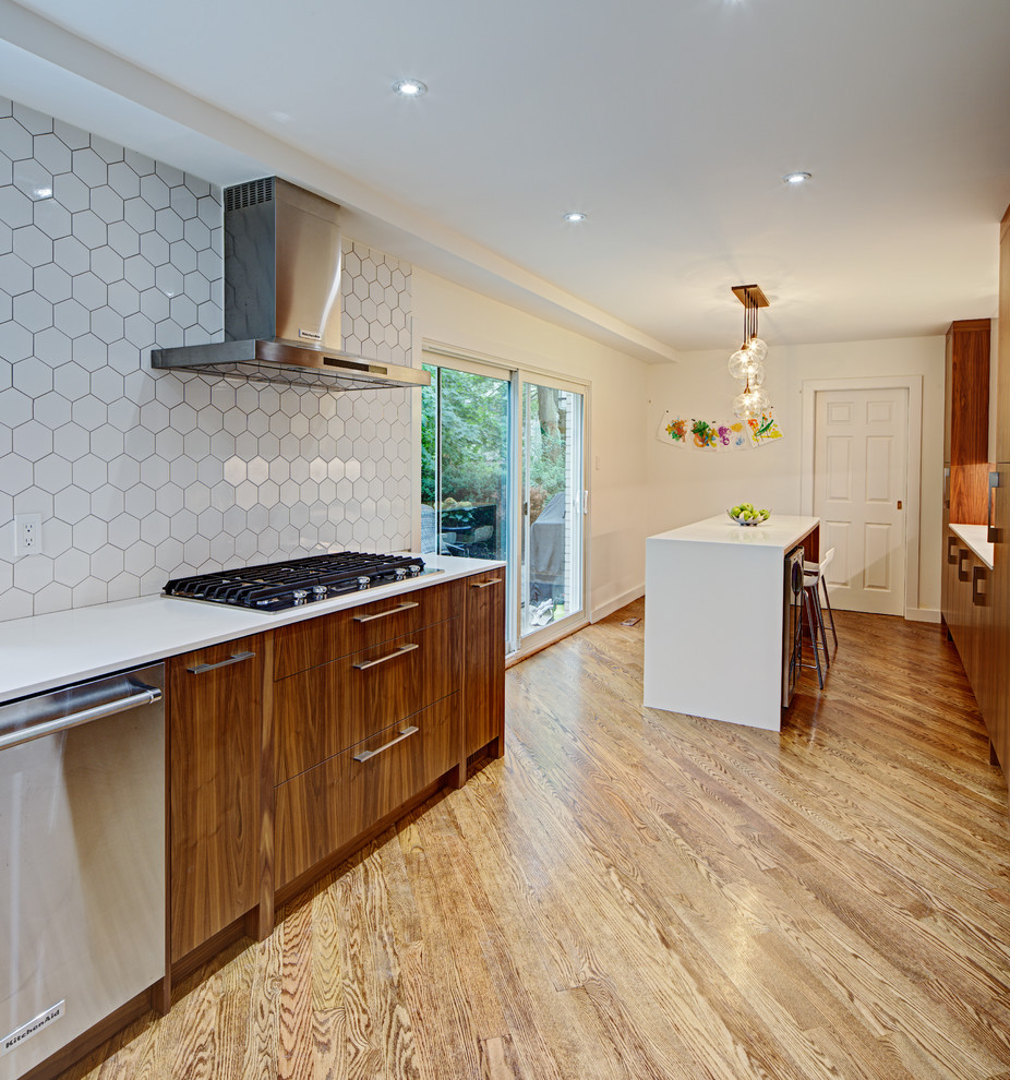 Modern inredning av ett kök, med släta luckor, skåp i mellenmörkt trä, bänkskiva i kvarts, beige stänkskydd, rostfria vitvaror och en köksö