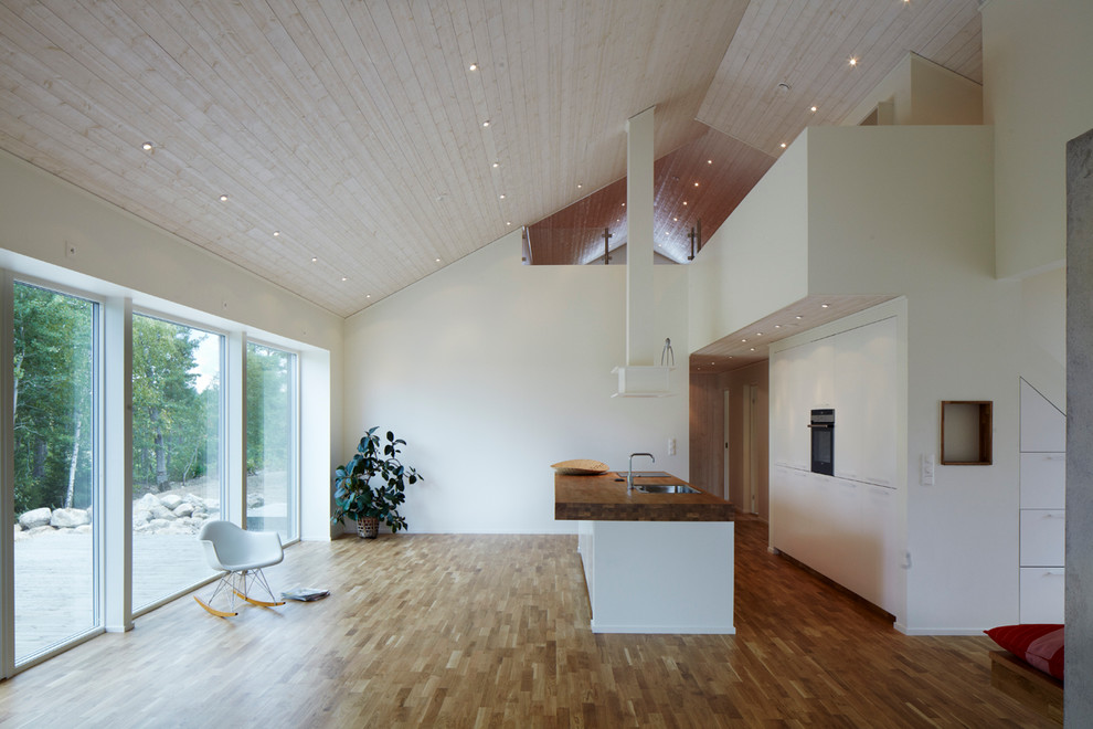 Idee per una cucina scandinava di medie dimensioni con lavello integrato, ante a filo, ante bianche, top in legno e pavimento in legno massello medio