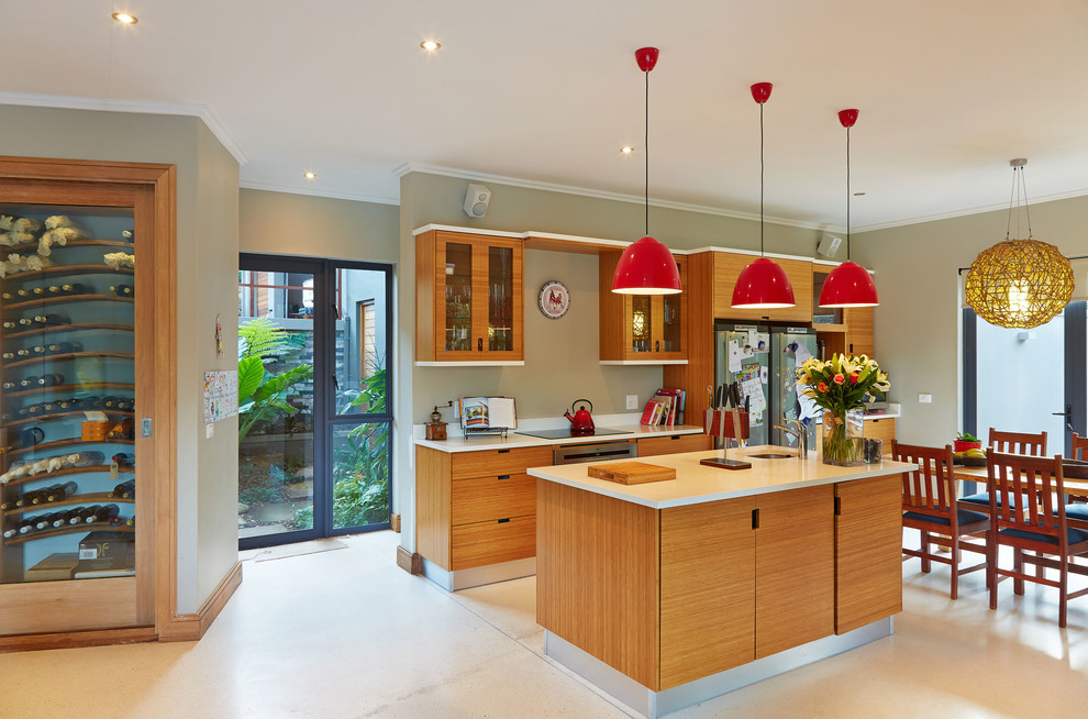 Moderne Wohnküche mit flächenbündigen Schrankfronten und hellbraunen Holzschränken in Sonstige
