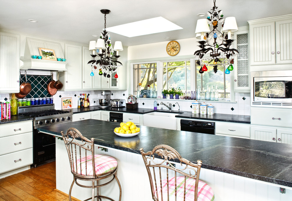 Klassische Küche mit flächenbündigen Schrankfronten, Landhausspüle und schwarzen Elektrogeräten in Santa Barbara